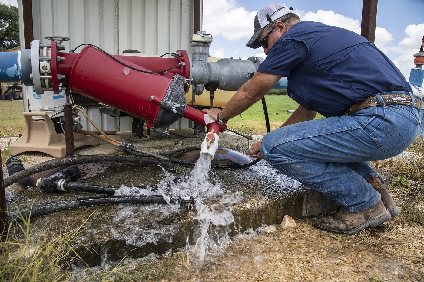 Un agricultor revisa la salida de agua de una bomba de riego.